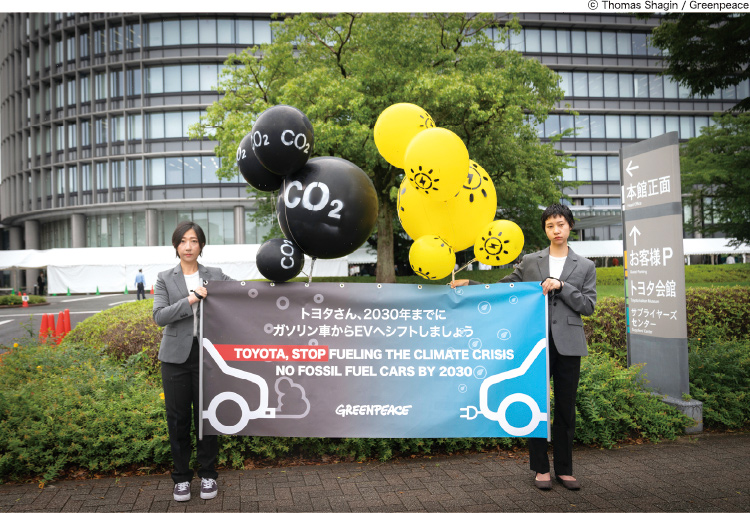 トヨタ自動車の株主総会に合わせ、同社本社前でEV転換の早期推進を訴えたメッセージを掲げた。（2023年6月14日）